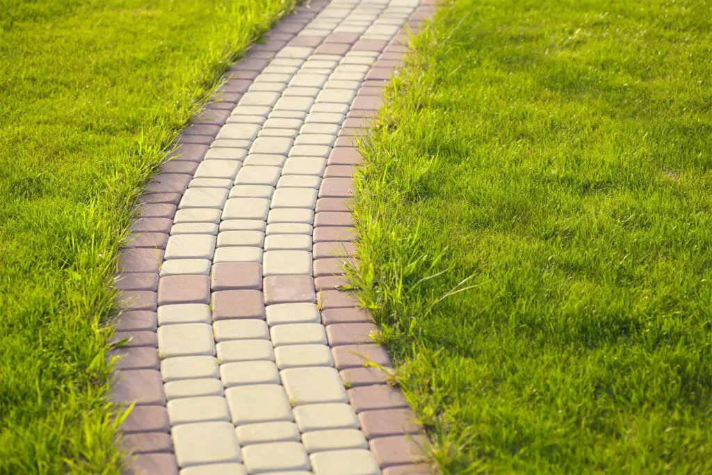 A charming walkway of interlocking brick pavers through a tranquil garden, highlighting brick paver walkways.