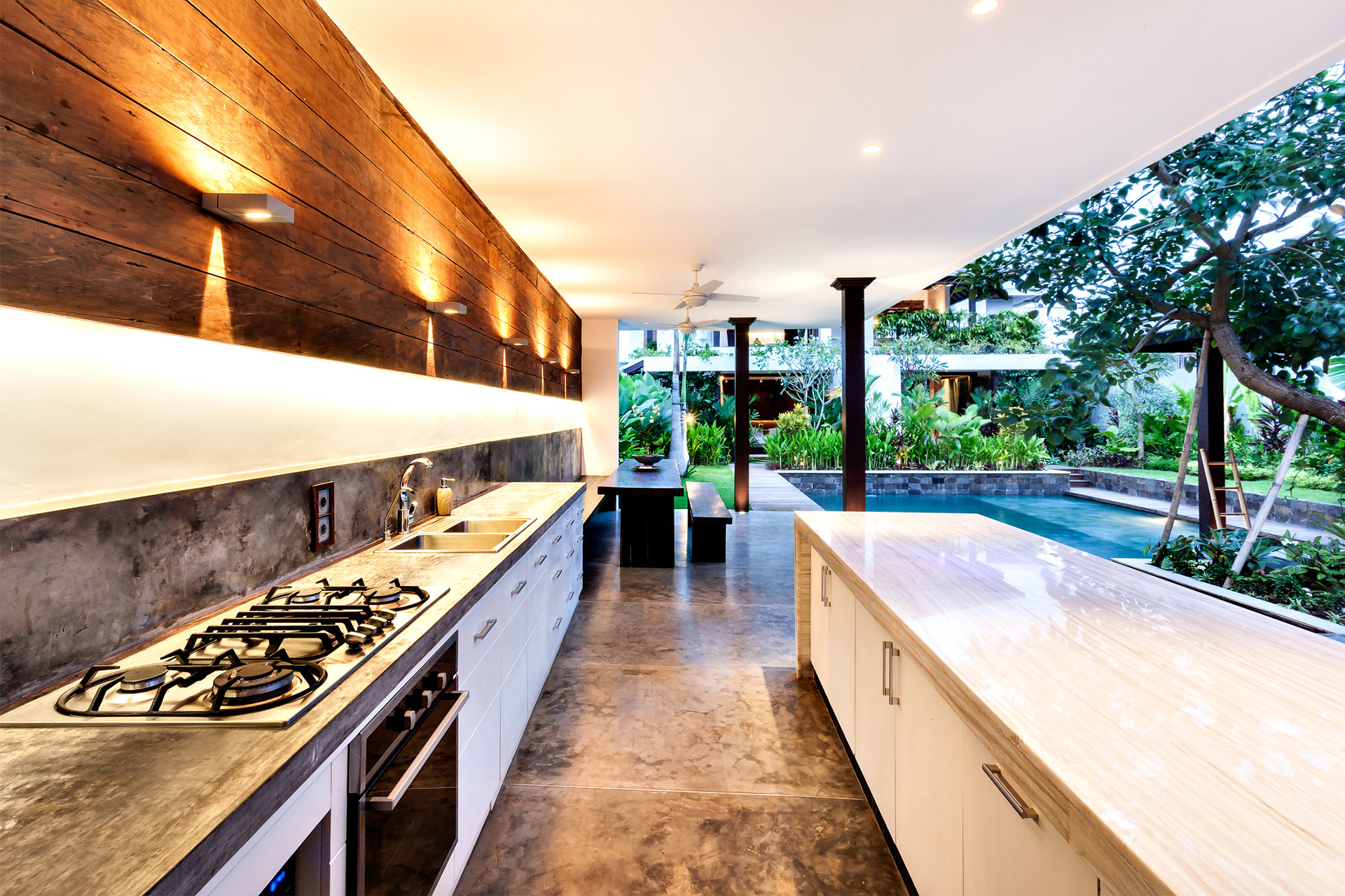 a modern outdoor kitchen setup with stainless steel appliances, granite countertops, and bar seating, nestled in a cozy patio area