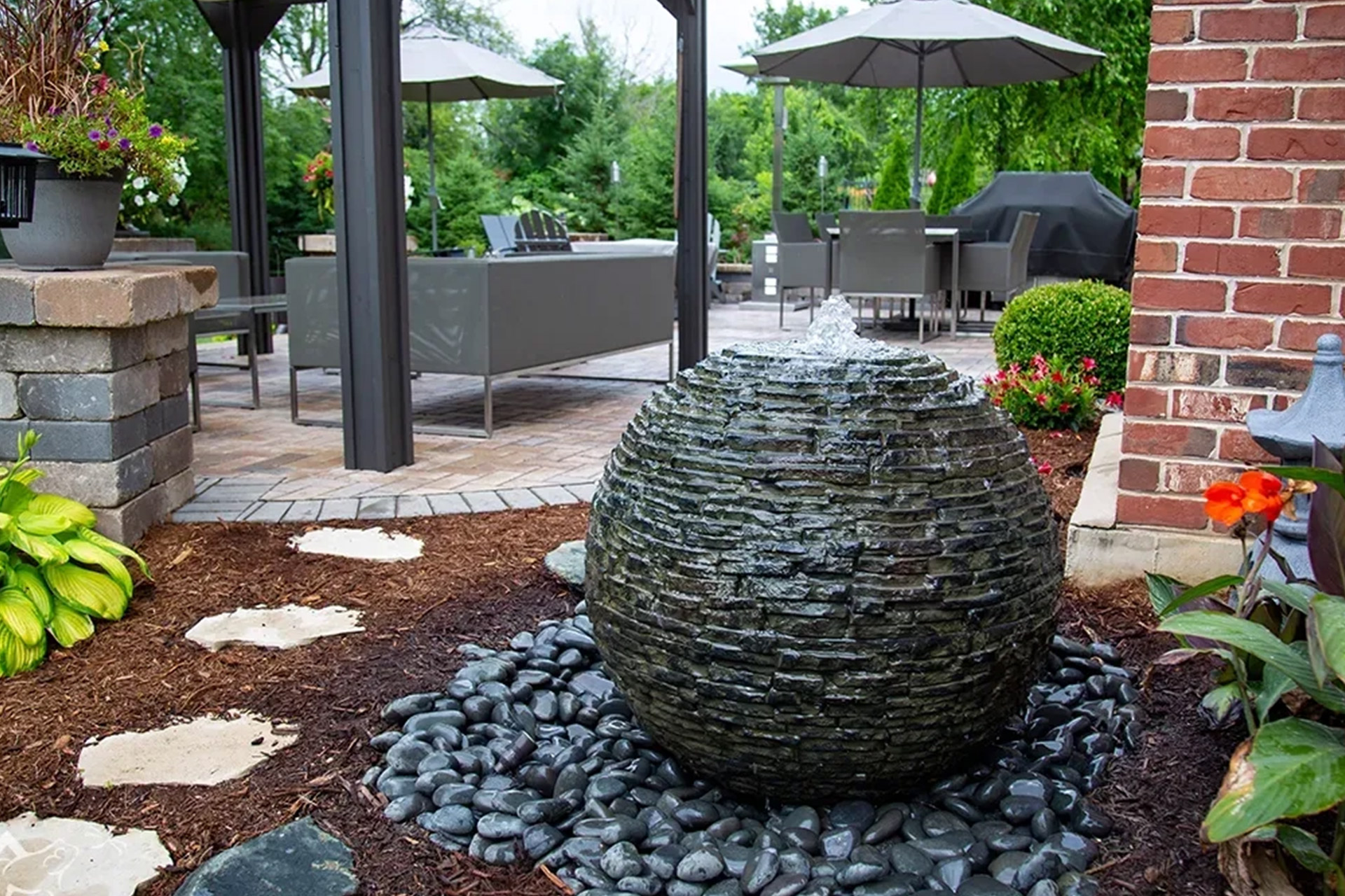 A big sphere rock water fountain as part of a backyard landscaping.