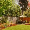 Beautifully designed backyard showcasing trees, shrubs, and lawn maintained through expert landscaping services for privacy.