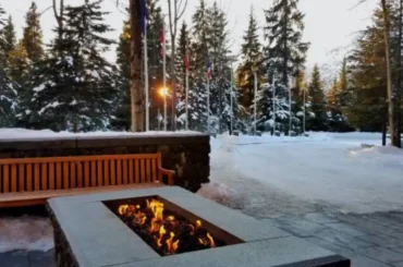 A professionally designed fire pit installation in a winter outdoor living space, surrounded by a serene snowy landscape and wooden seating.