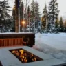 A professionally designed fire pit installation in a winter outdoor living space, surrounded by a serene snowy landscape and wooden seating.