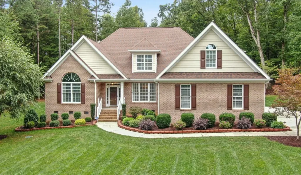 Front yard showing completed landscaping projects with paver walkway, manicured shrubs, and fresh mulch for improved curb appeal.