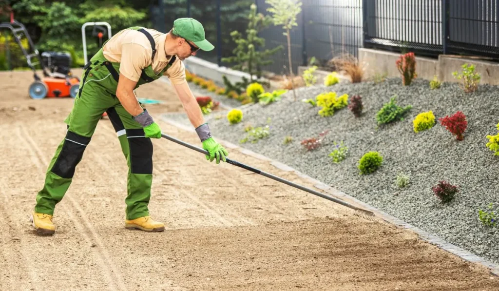 Professional performing landscape grading in a residential backyard to manage drainage.