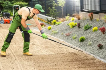 Professional performing landscape grading in a residential backyard to manage drainage.