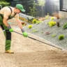 Professional performing landscape grading in a residential backyard to manage drainage.