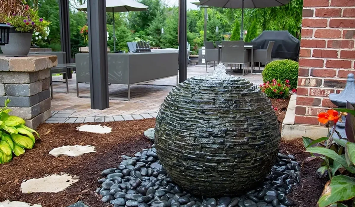 A big sphere rock water fountain as part of a backyard landscaping.